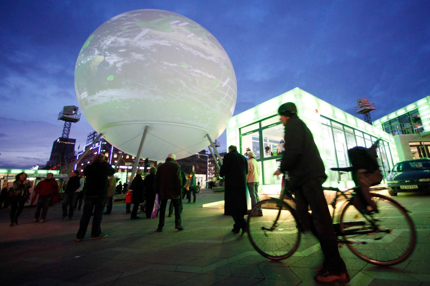 People walk past a large globe featuring an interactive display in central Copenhagen December 8, 2009. Copenhagen is the host city for the United Nations Climate Change Conference 2009, which lasts from December 7 until December 18. REUTERS/Bob Strong  (DENMARK ENVIRONMENT POLITICS SOCIETY) - GM1E5C904WT01