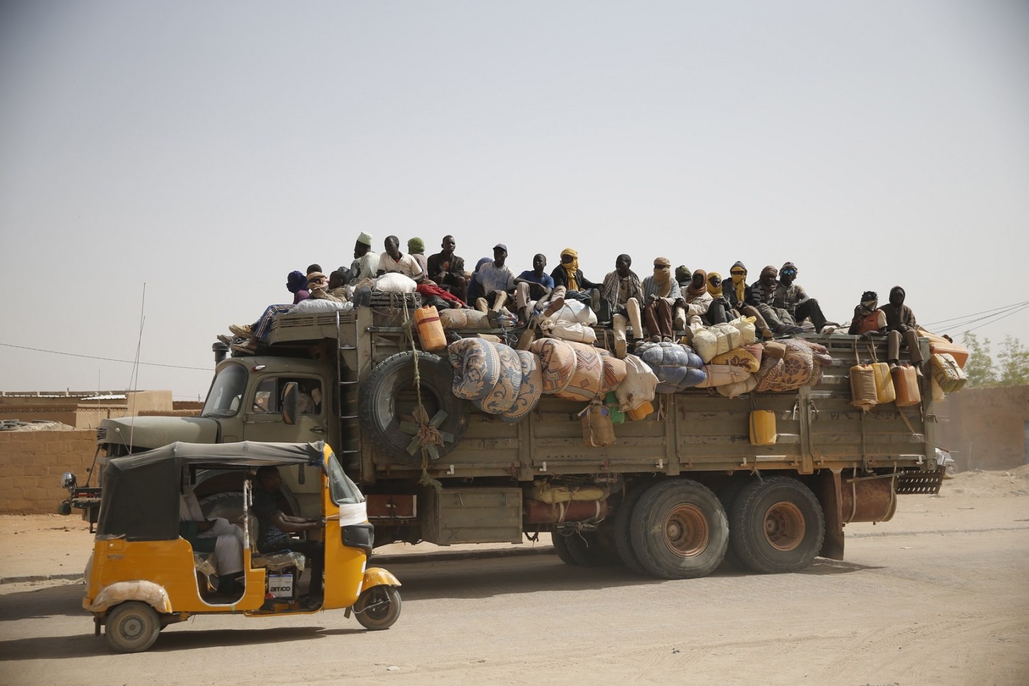 Migrants sit on their belongings in the back of a truck as it is driven through a dusty road in the desert town of Agadez, Niger May 25, 2015. African migrants in overcrowded pickup trucks, encouraged by social media messages from friends who survived the perilous journey across the Mediterranean, set off from Agadez, an ancient trading town on the edge of the Sahara, to cross Niger in the uncertain journey towards Europe via Libya, where the collapse of the government has offered an open door for smugglers. Mostly young men, escaping grinding poverty in neighbouring Benin or Burkina Faso, face bandits and often have to pay bribes en route, on top of the hefty payments to people smugglers. International focus on the issue of migration into Europe has sharpened after hundreds of migrants drowned while trying to cross the sea from North Africa in overcrowded and unsafe vessels. REUTERS/Akintunde Akinleye TPX IMAGES OF THE DAY PICTURE 35 OF 36 FOR WIDER IMAGE STORY SMUGGLED THROUGH NIGERSEARCH SAHARA AKINLEYE FOR ALL IMAGES TPX IMAGES OF THE DAY - GF10000110096