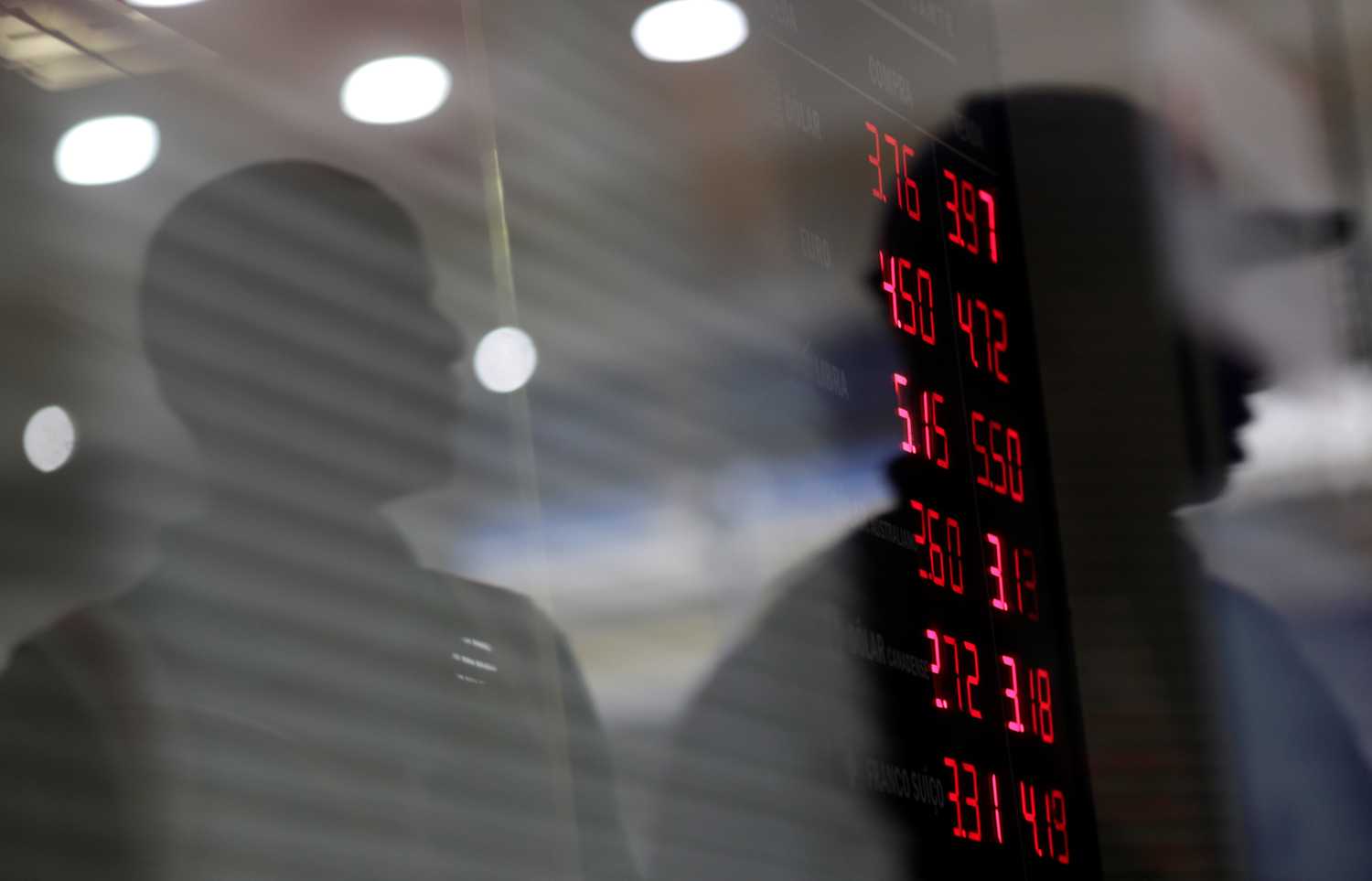 People are reflected on the glass as they read a board showing the Real-U.S. dollar and several foreign currencies exchange rates in Rio de Janeiro Brazil June 8, 2018. REUTERS/Ricardo Moraes - RC1696A6B060