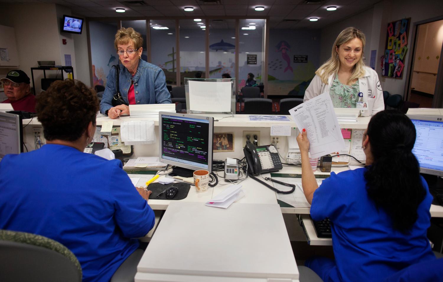 Two patients check in at a nurse's station