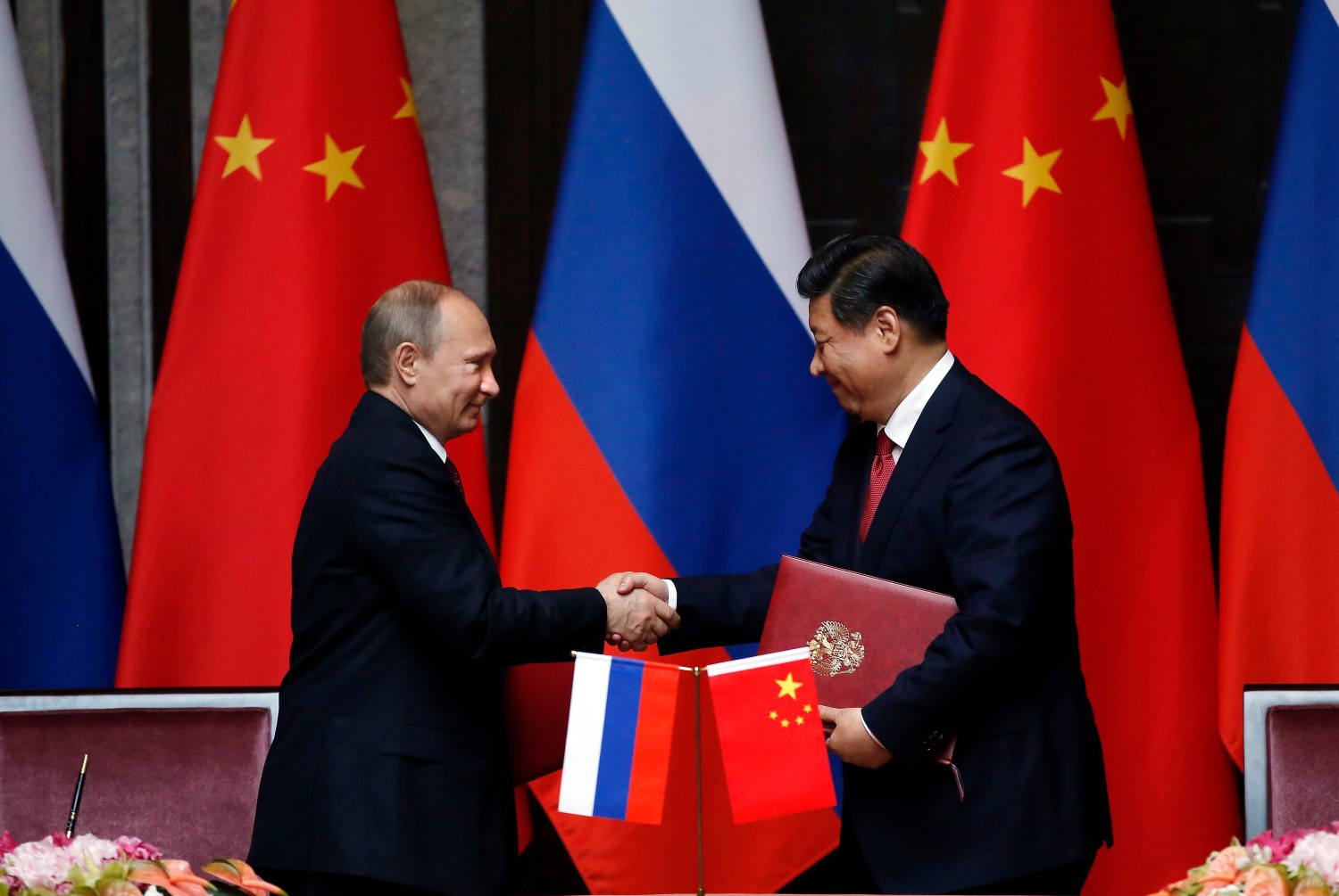 Russia's President Vladimir Putin (L) and China's President Xi Jinping shake hands after signing an agreement during a bilateral meeting at the Xijiao State Guesthouse ahead of the fourth Conference on Interaction and Confidence Building Measures in Asia (CICA) summit, in Shanghai May 20, 2014. Trade between China and Russia is expected to reach $100 billion by 2015, Xi said on Tuesday, after meeting with Putin. REUTERS/Carlos Barria  (CHINA - Tags: POLITICS BUSINESS) - GM1EA5K14XV01
