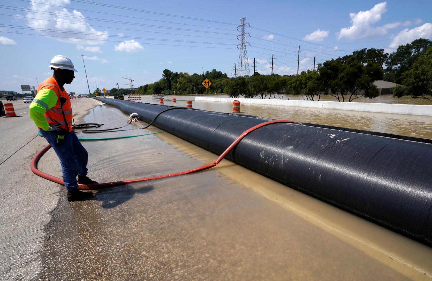 A Texas Department of Transportation worker monitors a temporary water filled dam keeping Harvey floodwaters from getting onto highway I-10 in Houston, Texas August 31, 2017. REUTERS/Rick Wilking - RC1FDAADF450