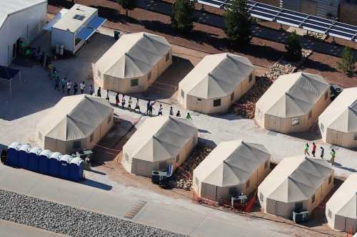 Immigrant children, many of whom have been separated from their parents under a new "zero tolerance" policy by the Trump administration, are shown walking in single file between tents in their compound next to the Mexican border in Tornillo, Texas, U.S. June 18, 2018.        REUTERS/Mike Blake - RC1A59D1E150