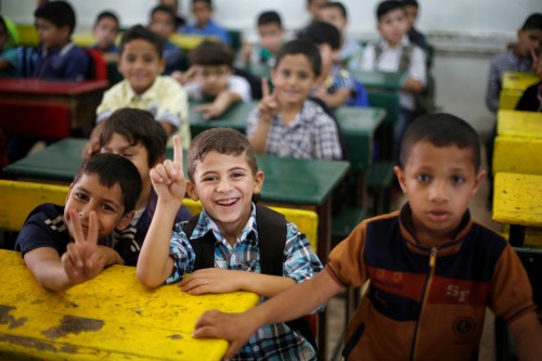 Schoolchildren react to the camera as they attend a lesson in a classroom on the first day of school