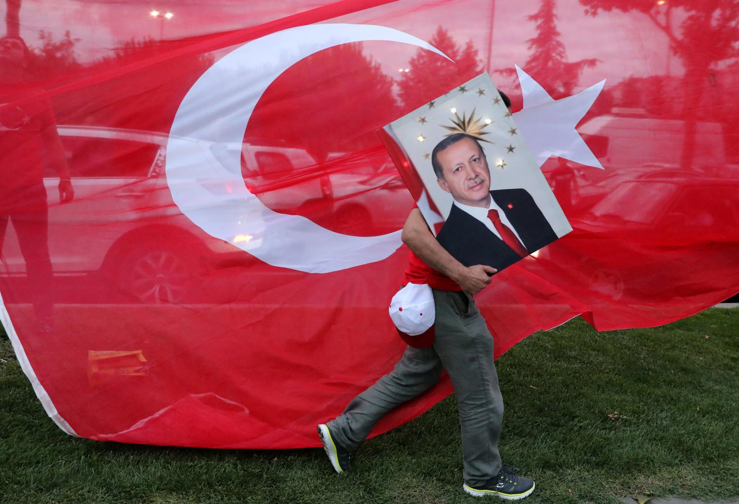A supporters of Turkish President Tayyip Erdogan holds his picture in front of a Turkish flag, in front of Turkey's ruling AK Party (AKP) headquarters in Istanbul,Turkey, June 24, 2018. REUTERS/Goran Tomasevic      TPX IMAGES OF THE DAY - RC1D72DCC500