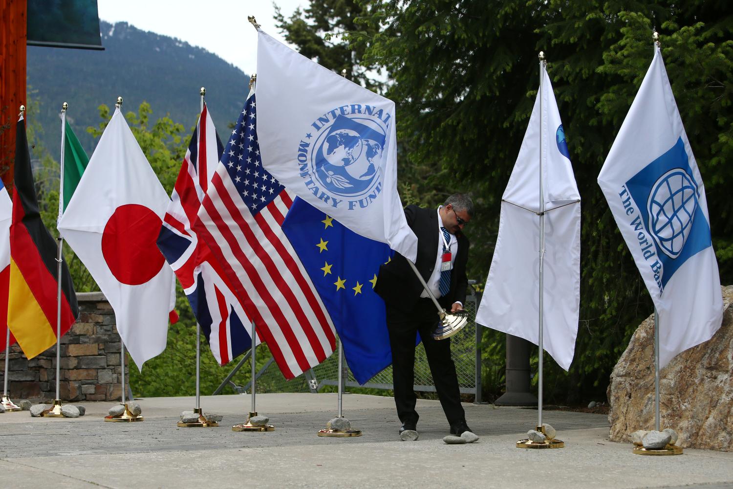 A security official picks up a flag after wind blew it over during the G7 Finance Ministers summit in Whistler, British Columbia, Canada, May 31, 2018.  REUTERS/Ben Nelms - RC1C003FD610