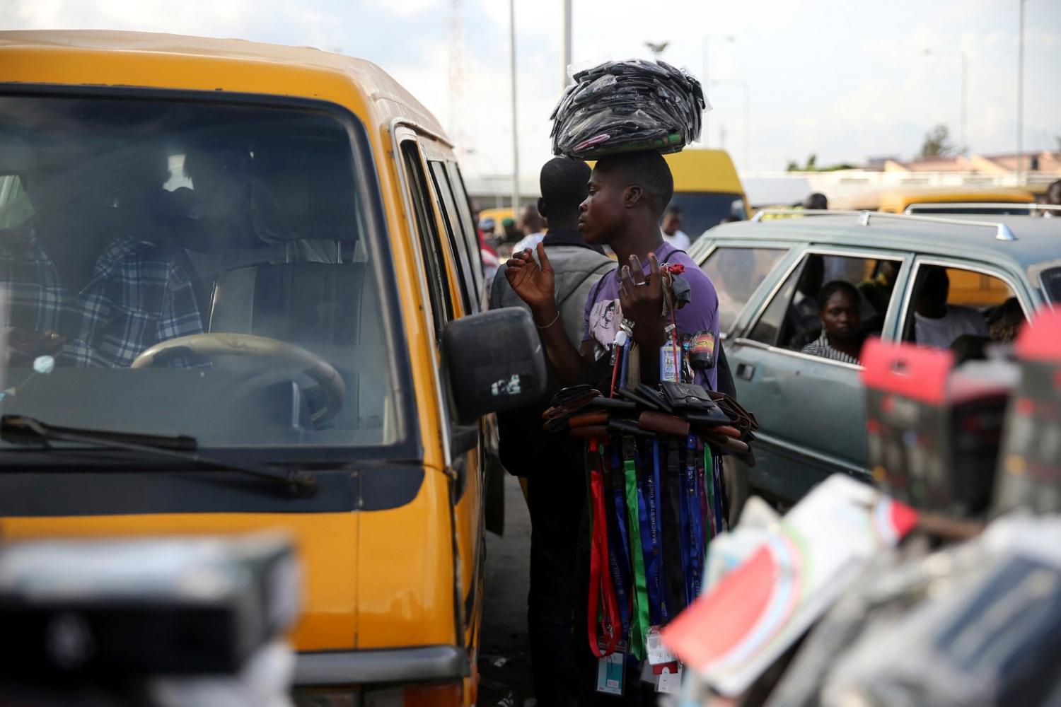 A man hawks his goods at a motor park in the Obalende district of Lagos October 9, 2013. With between 15 million and 21 million people - the upper estimate is the official one, though no one really knows - and generating a third of GDP for Africa's second biggest economy, Lagos has become almost as alluring to yield-hungry investors as it is to the 4,000 or so economic migrants who turn up each day. But it faces a daily challenge just trying to keep up with the pace of population growth, much of it on the edge of water. Nigeria, already pushing 170 million people, will be home to 400 million by 2050, making it the world's fourth most populous country, according to the global Population Reference Bureau (PRB). Lagos will have roughly doubled in size by then, Fashola and demographers agree. Picture taken October 9, 2013. To match Insight LAGOS-MEGACITY/    REUTERS/Akintunde Akinleye (NIGERIA - Tags: SOCIETY BUSINESS EMPLOYMENT) - GM1E9AN0J5R01