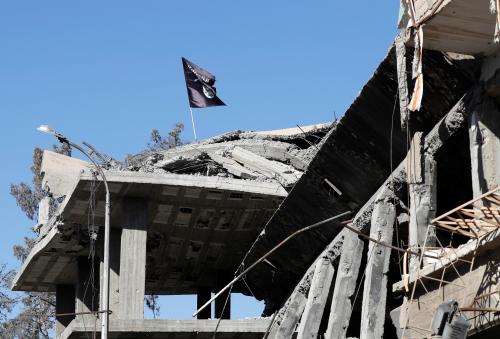 A flag of Islamic State militants is pictured above a destroyed house near the Clock Square in Raqqa, Syria October 18, 2017. Picture taken October 18, 2017.     REUTERS/Erik De Castro - RC159E696010