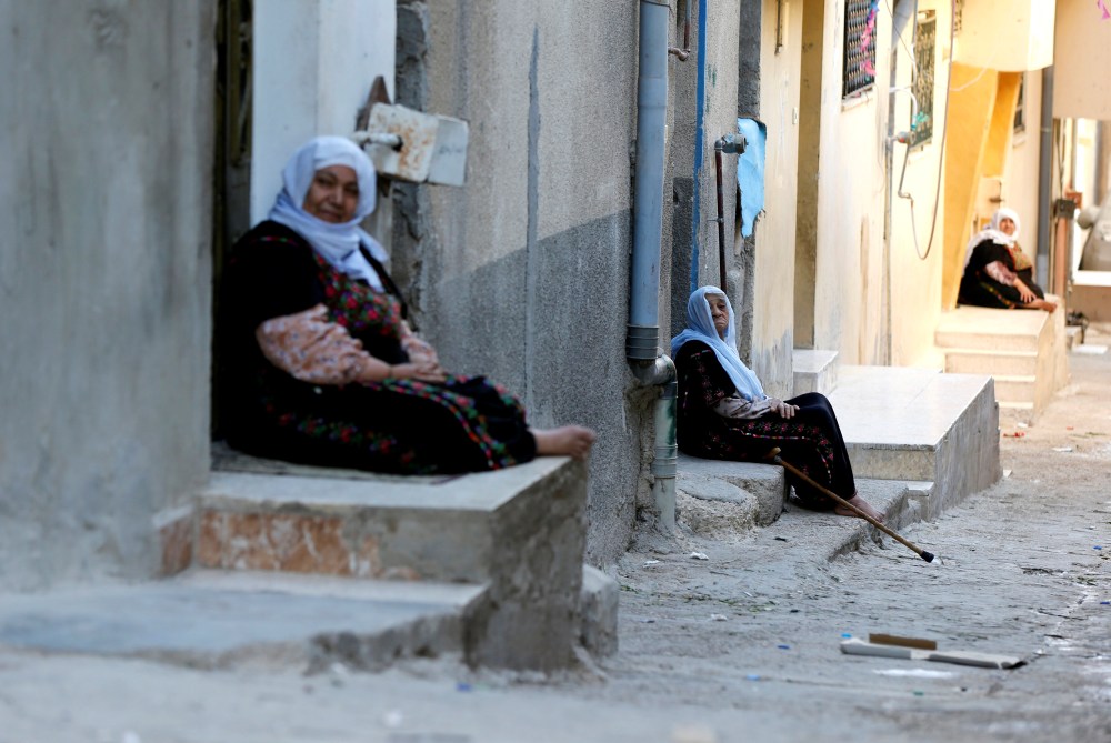 Palestinian refugee women sit if front their homes during the holy month of Ramadan, in Al-Baqaa Palestinian refugee camp, near Amman, Jordan, May 29, 2018. Reuters/Muhammad Hamed - RC19116CA0A0