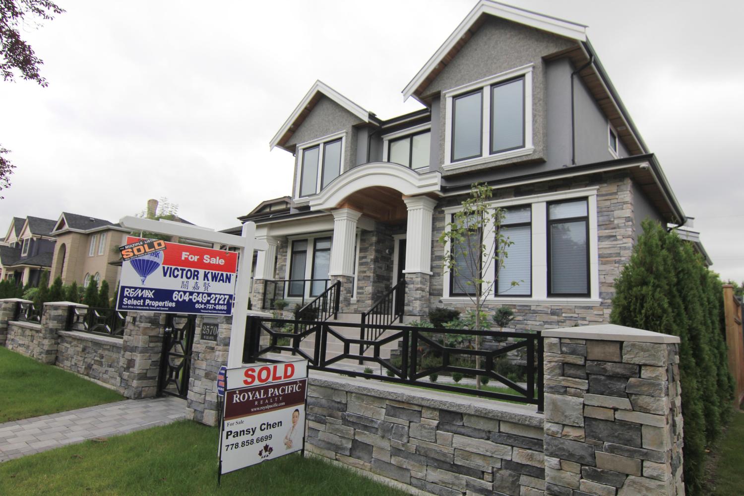 Realtors' signs are hung outside a newly sold neighborhood property.