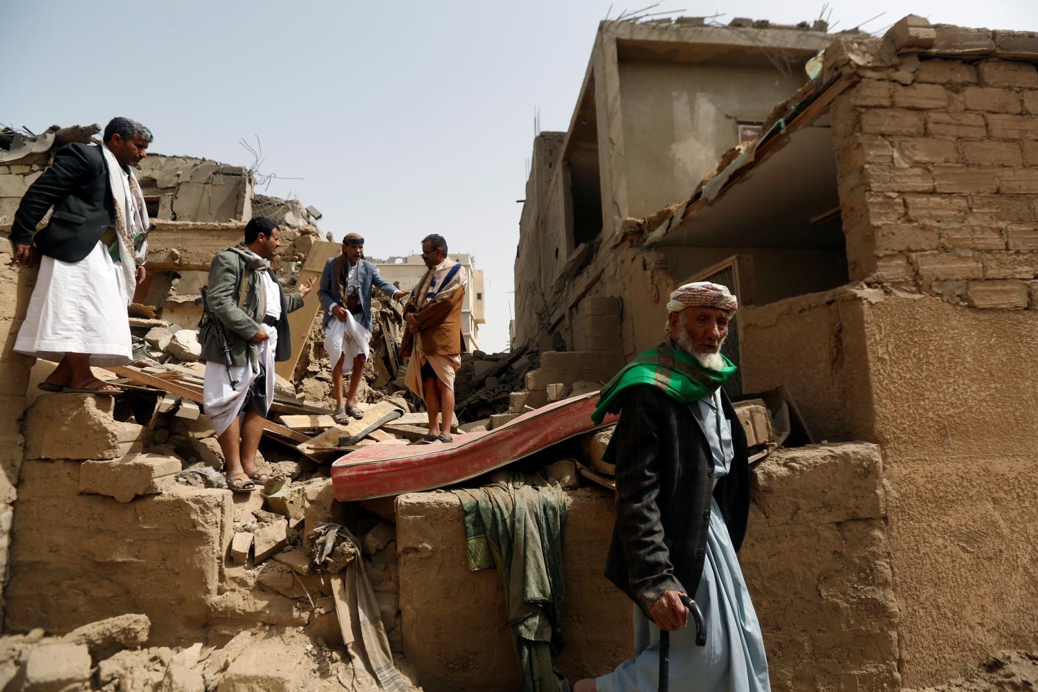 People stand on the rubble of a house destroyed by an air strike in Amran, Yemen June 25, 2018. REUTERS/Khaled Abdullah - RC1FD0EBED70