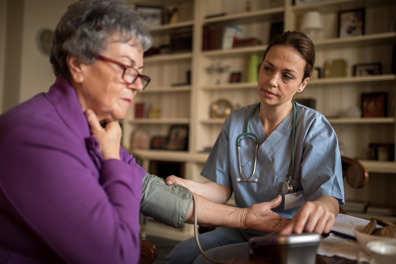 An old women does not feel well at home and young nurse taking care about her