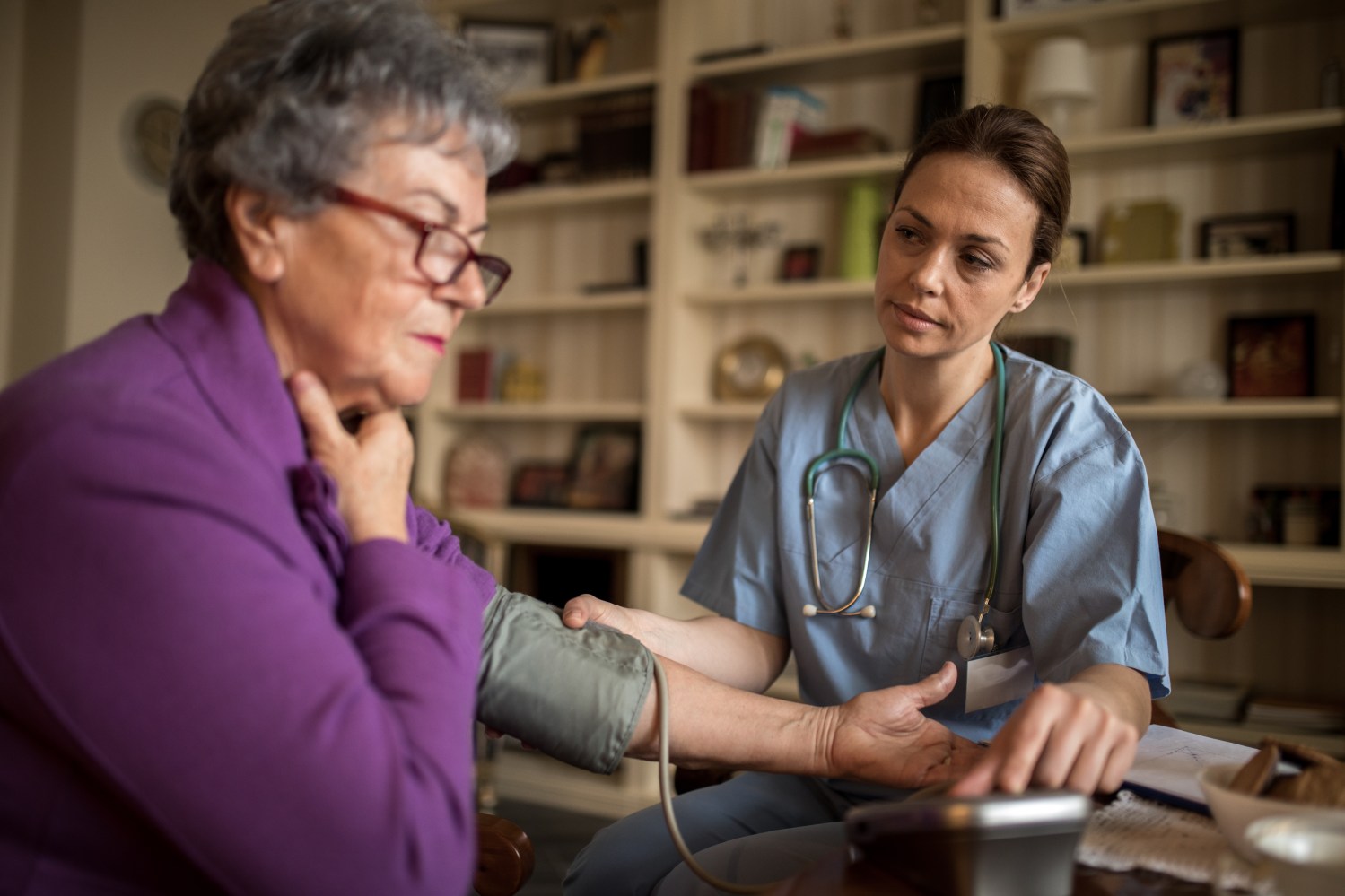 An old women does not feel well at home and young nurse taking care about her