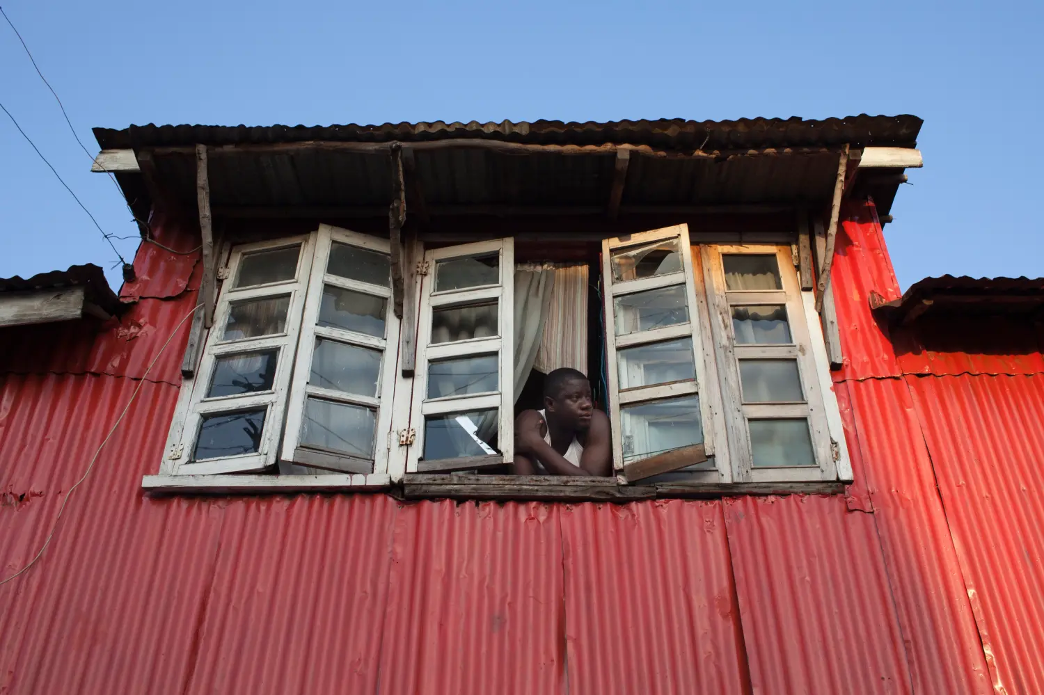 A man looks out of the window of his colonial-era house in Freetown, Sierra Leone November 19, 2012. Sierra Leone's elections were generally well conducted, saw a large turnout, and will help consolidate democracy in the West African state if the eventual results are accepted peacefully by the contenders, European Union observers said on Monday. REUTERS/Joe Penney (SIERRA LEONE - Tags: POLITICS ELECTIONS SOCIETY) - GM1E8BJ1MSC01