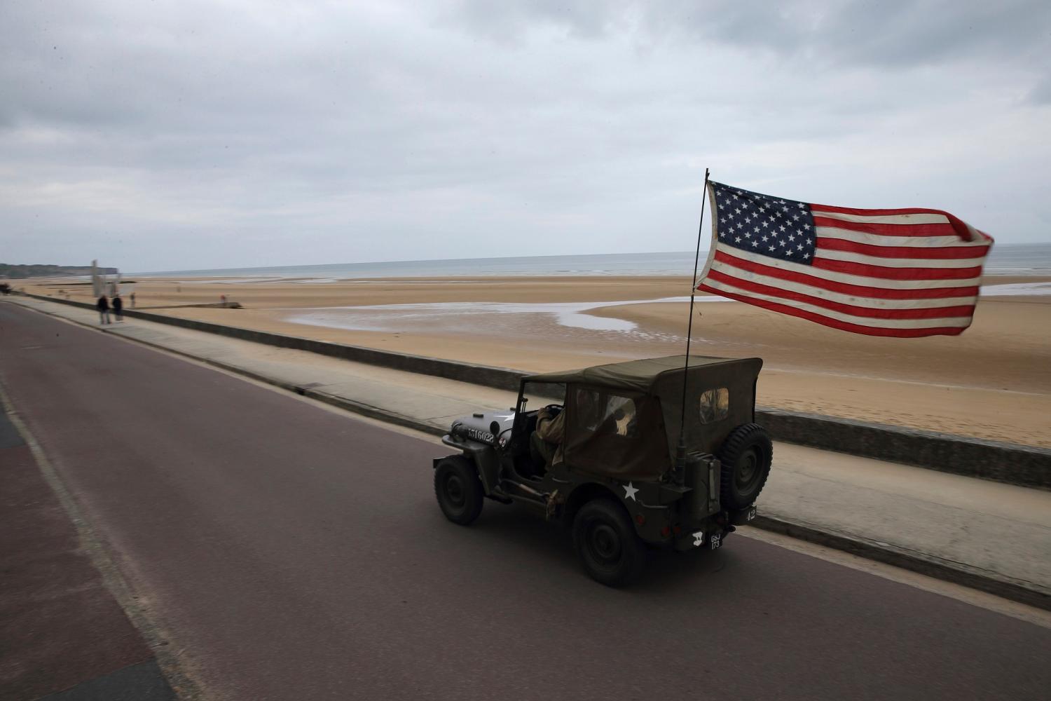 An American flag waves from the back of a jeep as a history enthusiast, drives on the road near Omaha beach in Saint-Laurent-sur-Mer, on the Normandy coast June 2, 2014. World leaders will attend ceremonies in Normandy June 6, 2014 marking the 70th anniversary of the World War Two allied beach landings on D-Day. REUTERS/Pascal Rossignol (FRANCE - Tags: CONFLICT ANNIVERSARY) - PM1EA621BKJ01