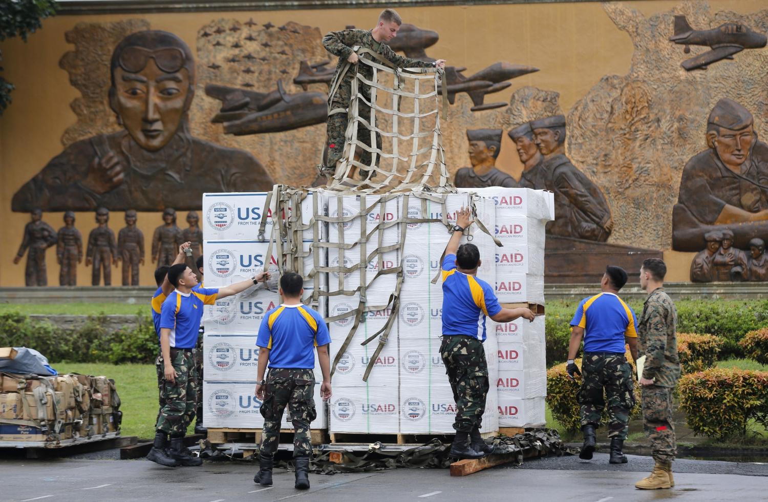 A U.S. Marine stands on top of boxes containing tent material from U.S. relief organisation USAid, as he and Philippine soldiers prepare the load to be deployed by airlift by U.S. military to victims of super typhoon Haiyan, at Manila airport November 13, 2013. Philippine officials have been overwhelmed by Haiyan, one of the strongest typhoons on record, which tore through the central Philippines on Friday and flattened Tacloban, coastal capital of Leyte province where officials had feared 10,000 people died, many drowning in a tsunami-like wall of seawater. REUTERS/Wolfgang Rattay (PHILIPPINES - Tags: DISASTER ENVIRONMENT MILITARY) - GM1E9BD0WA102