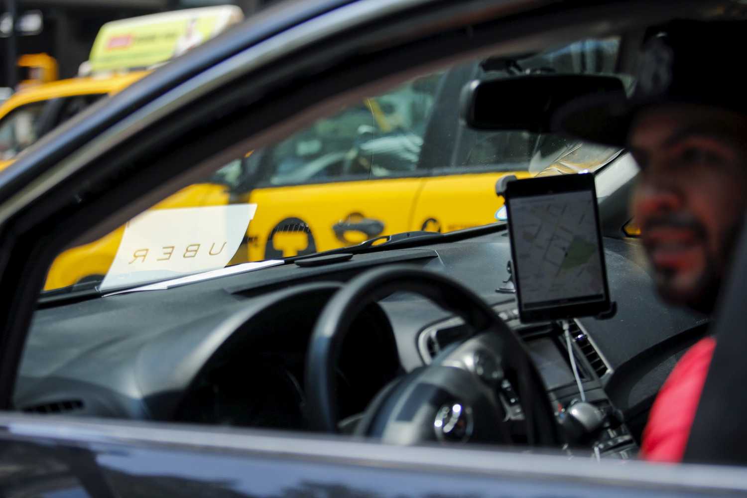 An Uber driver looks out of his vehicle next to New York City Hall while Uber riders and driver-partners take part in a rally on steps of the City Hall against proposed legislation limiting for-hire vehicles in New York June 30, 2015. REUTERS/Eduardo Munoz - GF10000144880