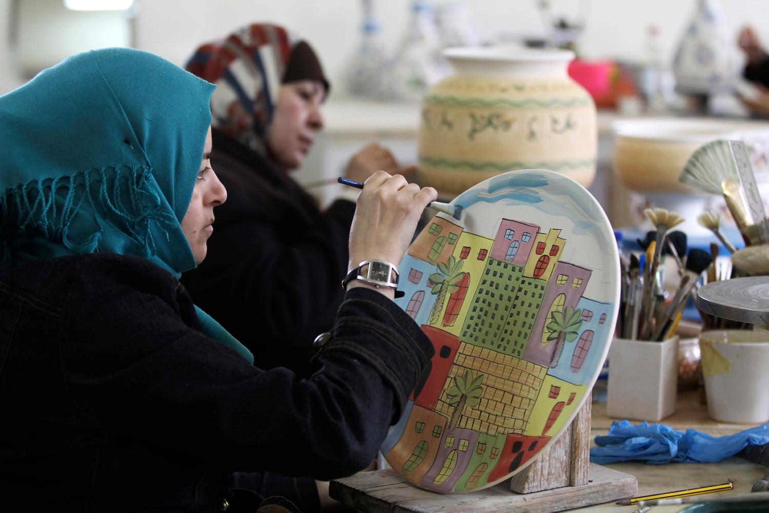 A Jordanian employee paints a handcrafted salver at a Beit al Bawadi ceramics workshop in Amman January 7, 2014. The Beit al Bawadi ceramic workshop was set up by non-profit organisation Jordanian Hashemite Fund for Human Development (JOHUD) to provide employment opportunities for Jordanian youths. REUTERS/Muhammad Hamed (JORDAN - Tags: SOCIETY BUSINESS EMPLOYMENT) - GM1EA1800K501