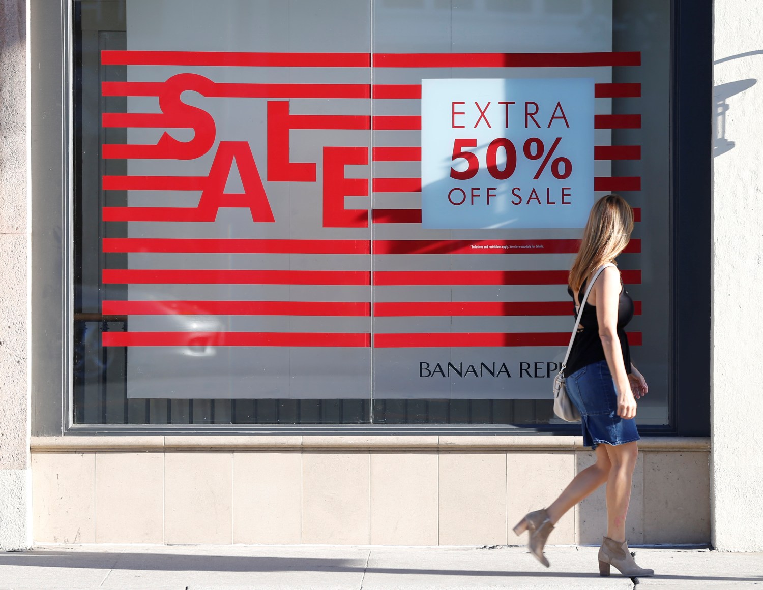 A woman walks past a sign advertising a sale in the Old Town shopping area of Pasadena, California, U.S. June 27, 2017.  REUTERS/Mario Anzuoni - RC16547F38A0