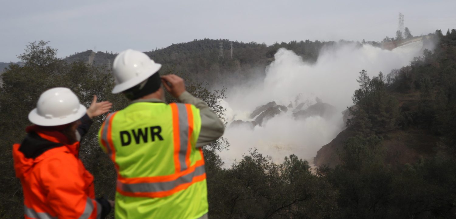 Staff with the California Department of Water Resources watch as water is released from the Lake Oroville Dam.