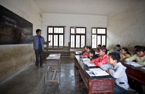 Xu Liangfan, 37, teaches students during a mathematics class at Banpo Primary School in Shengji county, Bijie city, in Guizhou province March 12, 2013. Xu, who started working at the school last year, is the headmaster of the school and teaches mathematics and gym class. Located halfway up a mountain, the school has 68 students of which about 20 live in the nearby Gengguan village. Students from Gengguan have to edge their way along the narrow cliff path to go to class everyday, alongside Xu who would escort them. The path, which was carved from cliffs over 40 years ago, is the only route between Gengguan village and the school, according to local media. Picture taken March 12, 2013. REUTERS/Stringer (CHINA - Tags: EDUCATION) CHINA OUT. NO COMMERCIAL OR EDITORIAL SALES IN CHINA - GM1E93Q10VQ01