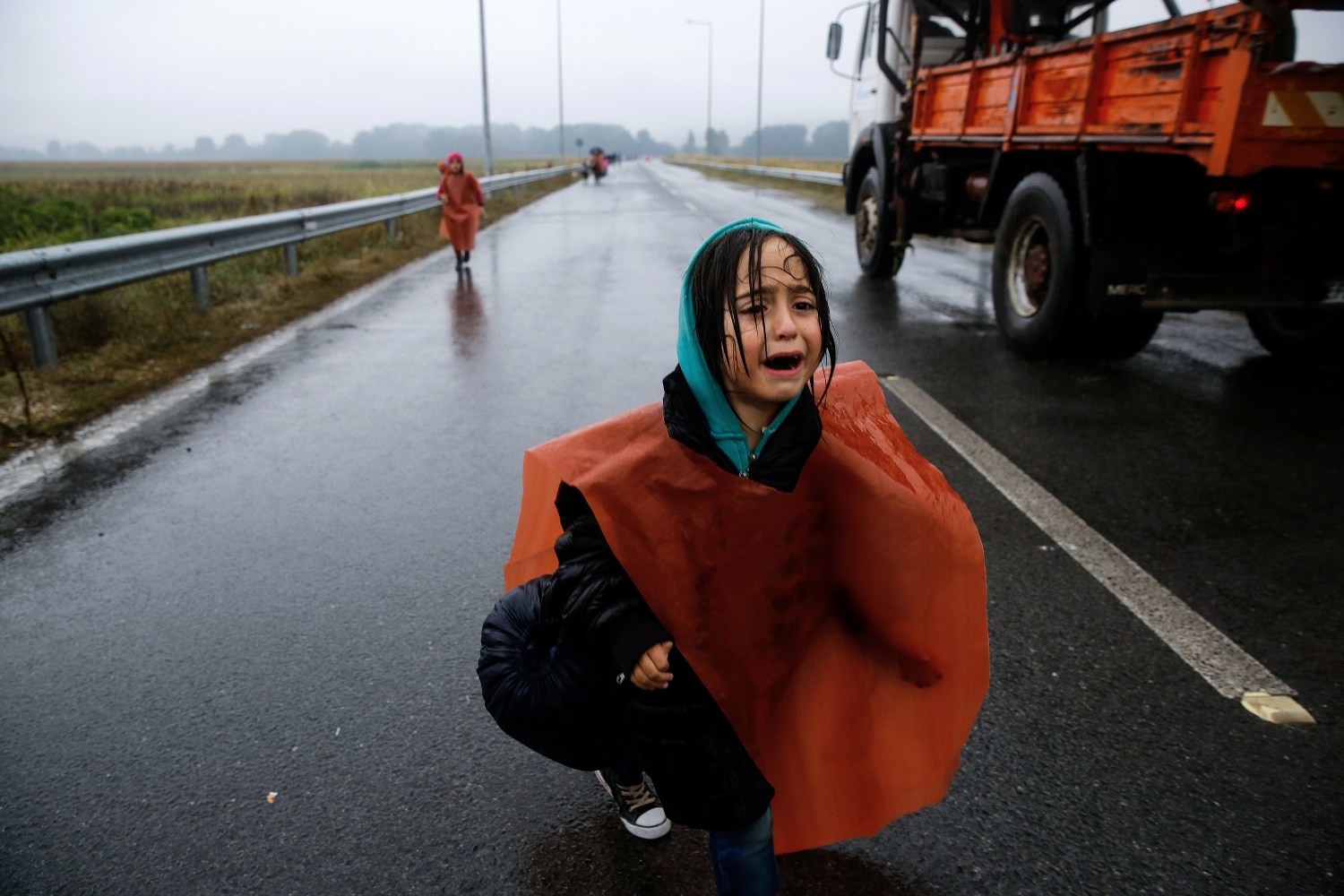 A Syrian refugee girl who was briefly separated from her parents cries as she walks through a rainstorm towards Greece's border with Macedonia, near the Greek village of Idomeni, September 10, 2015. Thousands of refugees and migrants, including many families with young children, have been left soaked after spending the night sleeping in the open in torrential rain on the Greek-Macedonian border. About 7,000 people waited in the mud of an open field near the northern Greek village of Idomeni to cross the border, with more arriving in trains, buses and taxis, as Macedonian police has imposed rationing in the flow of refugees.  REUTERS/Yannis Behrakis - S1BEUGOKOIAA