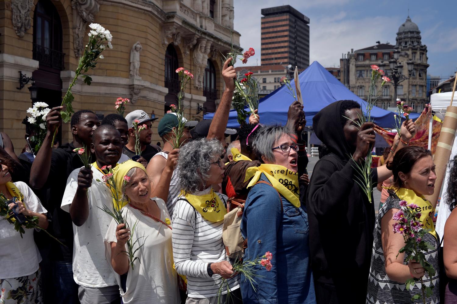 Migrants and members of the Basque NGO Ongi Etorri Errefuxiatuak (Welcome Refugees) hold flowers representing migrants drowned in the Mediterranean sea, during a 24 hour vigil in Bilbao, Spain, July 29, 2018. REUTERS/Vincent West - RC12B30F5B00