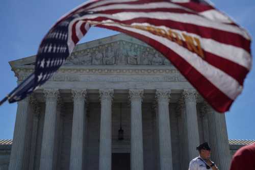 A man holds a flag outside the U.S. Supreme Court, as the Trump v. Hawaii case regarding travel restrictions in the U.S. remains pending, in Washington, U.S., June 25, 2018. REUTERS/Toya Sarno Jordan     TPX IMAGES OF THE DAY - RC17036C7760