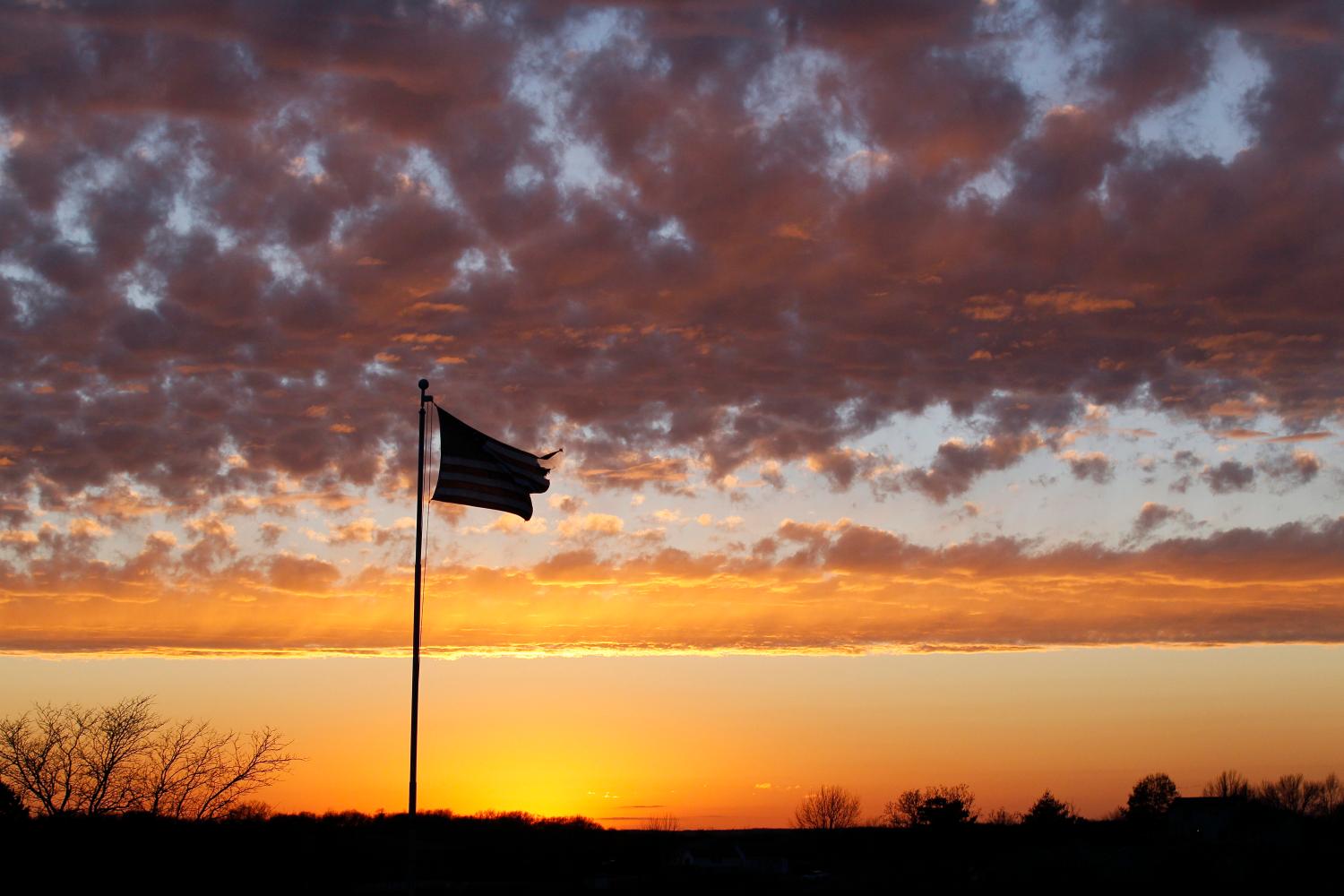 A tattered American flag flies at sunset over a military veterans' cemetery outside of Knoxville, Iowa December 31, 2011. REUTERS/Rick Wilking (UNITED STATES - Tags: SOCIETY) - GM1E8110M1U01