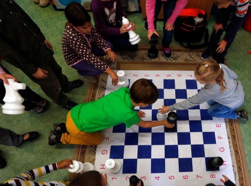 Children play chess at a classroom in the Dezso Lemhenyi school, which uses the new Chess Palace teaching programme of the world's best female chess player Judit Polgar, in Budapest October 15, 2013. With names like Jumpy Horse, Boom Rook and Tiny Pawn, pieces in the Chess Palace come to life and are like close friends who guide the children through difficult school subjects. They range in size from 1 cm (under half an inch) tall to a meter (three feet) in height. Chairs, walls and carpets also sport chess motifs. The pieces, whose combinations and moves represent mathematical, linguistic or musical patterns, help children develop their skills in chess and in their school studies while making the learning process a more joyous exercise. Picture taken October 15, 2013.REUTERS/Laszlo Balogh (HUNGARY - Tags: SPORT CHESS EDUCATION SOCIETY) - GM1E9AO1NK501