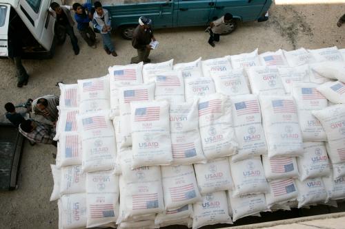 People stand beside a truck loaded with sacks of flour received from The United States Agency for International Development (USAID).