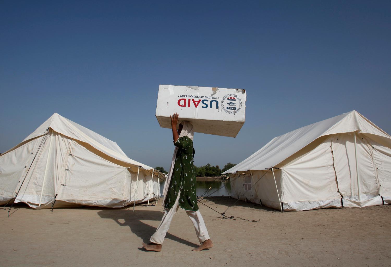 A woman, who has been displaced by floods, uses a USAID box to move her belongings while taking refuge on an embankment at Chandan Mori village in Dadu, some 320 km (199 miles) north of Karachi October 10, 2010. REUTERS/Akhtar Soomro (PAKISTAN - Tags: DISASTER ENVIRONMENT) - GM1E6AA1O2701