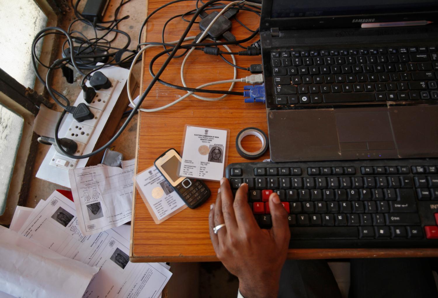 An operator works on his table while enrolling villagers for the Unique Identification (UID) database system at an enrolment centre at Merta district in the desert Indian state of Rajasthan February 21, 2013. In a more ambitious version of programmes that have slashed poverty in Brazil and Mexico, the Indian government has begun to use the UID database, known as Aadhaar, to make direct cash transfers to the poor, in an attempt to cut out frauds who siphon billions of dollars from welfare schemes. Picture taken February 21, 2013. REUTERS/Mansi Thapliyal (INDIA - Tags: SOCIETY POVERTY SCIENCE TECHNOLOGY BUSINESS) - GM1E92S1AM201