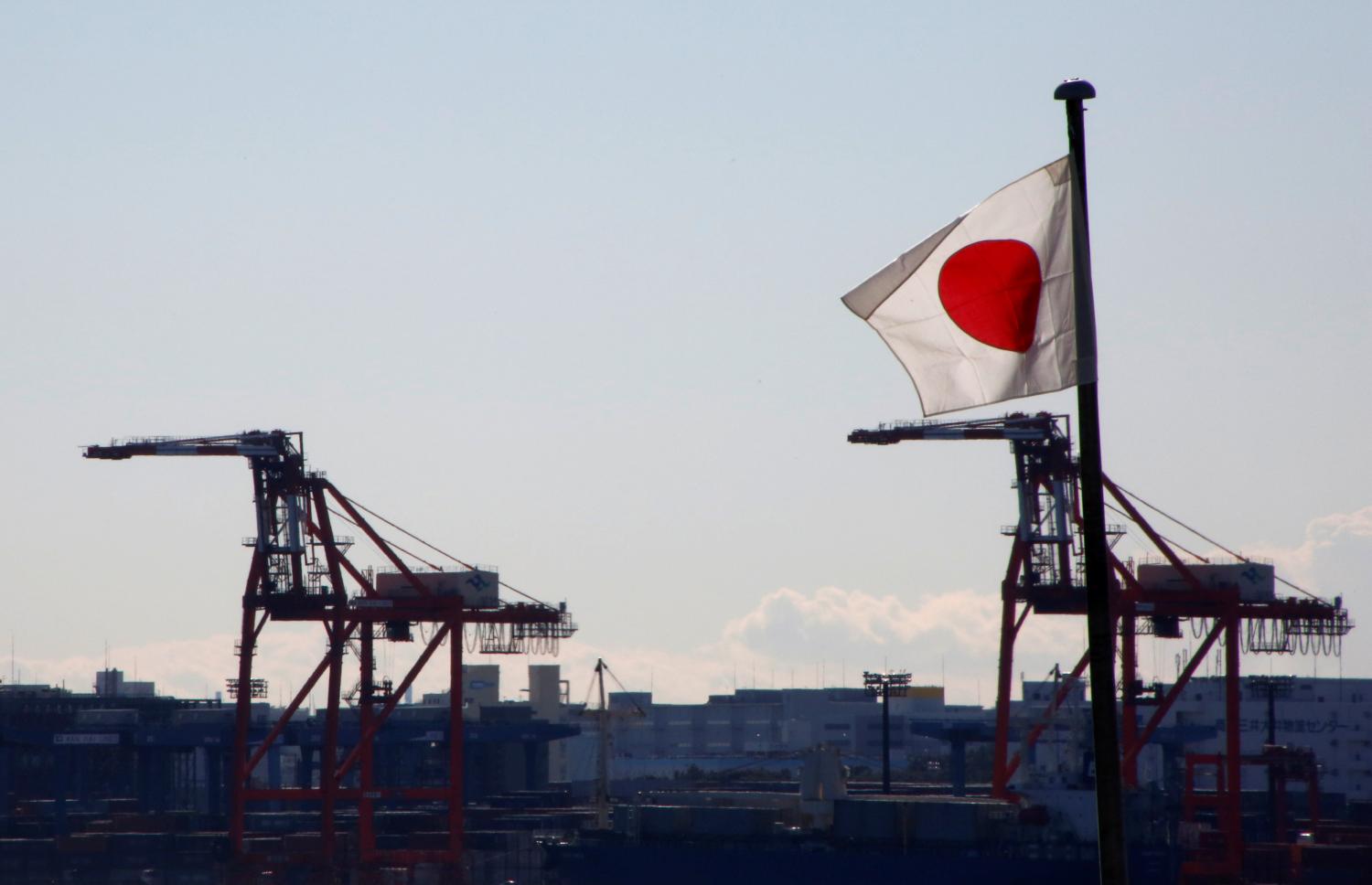 Japan's national flag is seen in front of containers and cranes at an industrial port in Tokyo, Japan, January 25, 2017. REUTERS/Kim Kyung-Hoon