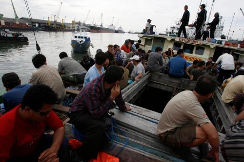 Indonesian marine police officers guard Afghan and Iranian asylum seekers after their boat was detained off Java island at Tanjung Perak port in Surabaya, East Java, May 2, 2010.  Indonesian police detained 75 migrants, including the asylum seekers, on Sunday for attempting to illegally enter Australia to seek asylum, police said. REUTERS/Sigit Pamungkas  (INDONESIA - Tags: CRIME LAW SOCIETY) - GM1E6521L6J01