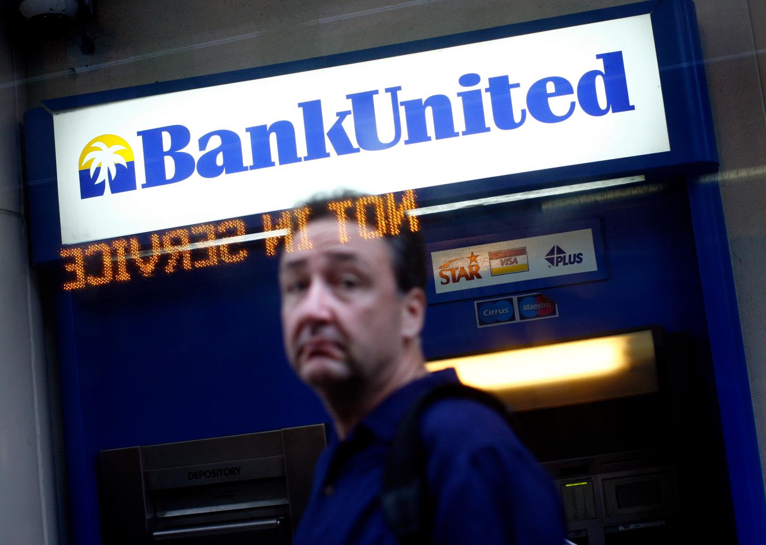 A pedestrian walks in front of a BankUnited branch in downtown Miami, Florida May 22, 2009. Florida-based BankUnited, which was closed by the U.S. government and sold to investors, was conducting business as usual on Friday and there was no sign of panic among customers, its new chief executive said. Banking industry veteran John Kanas, who also took over as chairman, told Reuters that BankUnited planned no immediate layoffs among its work force of 1,100 and expected to expand branches in its Miami base while closing branches outside the city. REUTERS/Carlos Barria  (UNITED STATES POLITICS BUSINESS) - GM1E55N06MB01