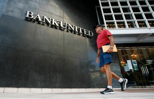 A pedestrian walks in front of the BankUnited headquarters in Coral Gables, Florida May 21, 2009. U.S. bank regulators on Thursday closed troubled lender BankUnited Financial Corp, Florida's largest bank, and sold its banking operations to a private equity consortium that includes WL Ross & Co. BankUnited, which had $12.8 billion in assets and $8.6 billion in retail deposits, is the biggest of 34 U.S. banks to fail so far this year. The Federal Deposit Insurance Corp said it estimates BankUnited's failure will cost its insurance fund $4.9 billion. REUTERS/Carlos Barria (UNITED STATES BUSINESS POLITICS) - GM1E55M0MI401