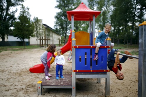 Four-year old Tom (R) and his six-year old sister Lisa from Offenbach show Serbian refugee Dragan (2nd L) and his sister Tamara (L) how to play on the climbing frame at a refugee camp in Hanau, Germany, August 18, 2015. Tom and Lisa learned from her mother that a lot of refugees come to Germany and most of them, especially the children, don't have much clothes or toys to play with. The two German youngsters than decided to visit the refugee camp to donate from their own wardrobe and toys and "make friends" with the kids from abroad.   REUTERS/Kai Pfaffenbach  - GF10000175689