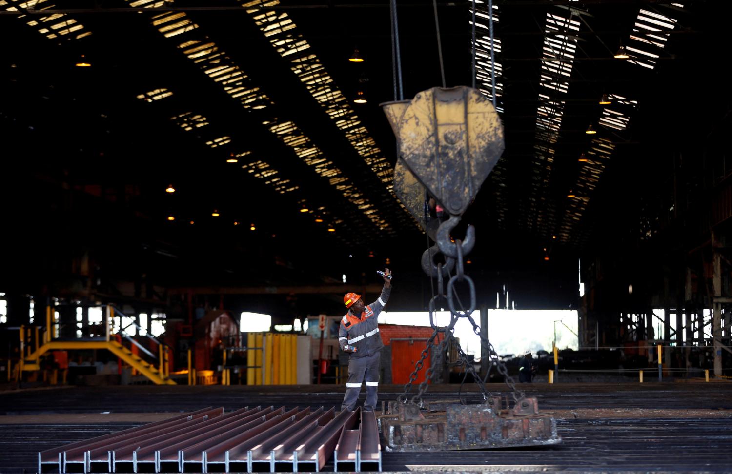 FILE PHOTO: A worker gestures in front of steel bars at a Highveld Steel plant, which has a manufacturing agreement with ArcelorMittal steel company, in Middleburg, South Africa June 6, 2017. REUTERS/Siphiwe Sibeko/File Photo - RC1C7C2AB6F0