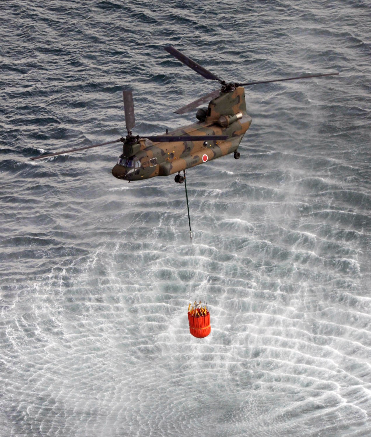A Japan Air Self-Defense Force CH-47 Chinook helicopter collects water from the ocean to drop on the reactors at the Fukushima Daiichi nuclear plant in Fukushima March 17, 2011. Operators of the quake-crippled nuclear plant in Japan again deployed military helicopters on Thursday in a bid to douse overheating reactors, as U.S. officials warned of the rising risk of a catastrophic radiation leak from spent fuel rods.  REUTERS/Yomiuri (JAPAN - Tags: MILITARY DISASTER ENVIRONMENT ENERGY IMAGES OF THE DAY) FOR EDITORIAL USE ONLY. NOT FOR SALE FOR MARKETING OR ADVERTISING CAMPAIGNS. THIS IMAGE HAS BEEN SUPPLIED BY A THIRD PARTY. IT IS DISTRIBUTED, EXACTLY AS RECEIVED BY REUTERS, AS A SERVICE TO CLIENTS. JAPAN OUT. NO COMMERCIAL OR EDITORIAL SALES IN JAPAN - GM1E73H0VIG01