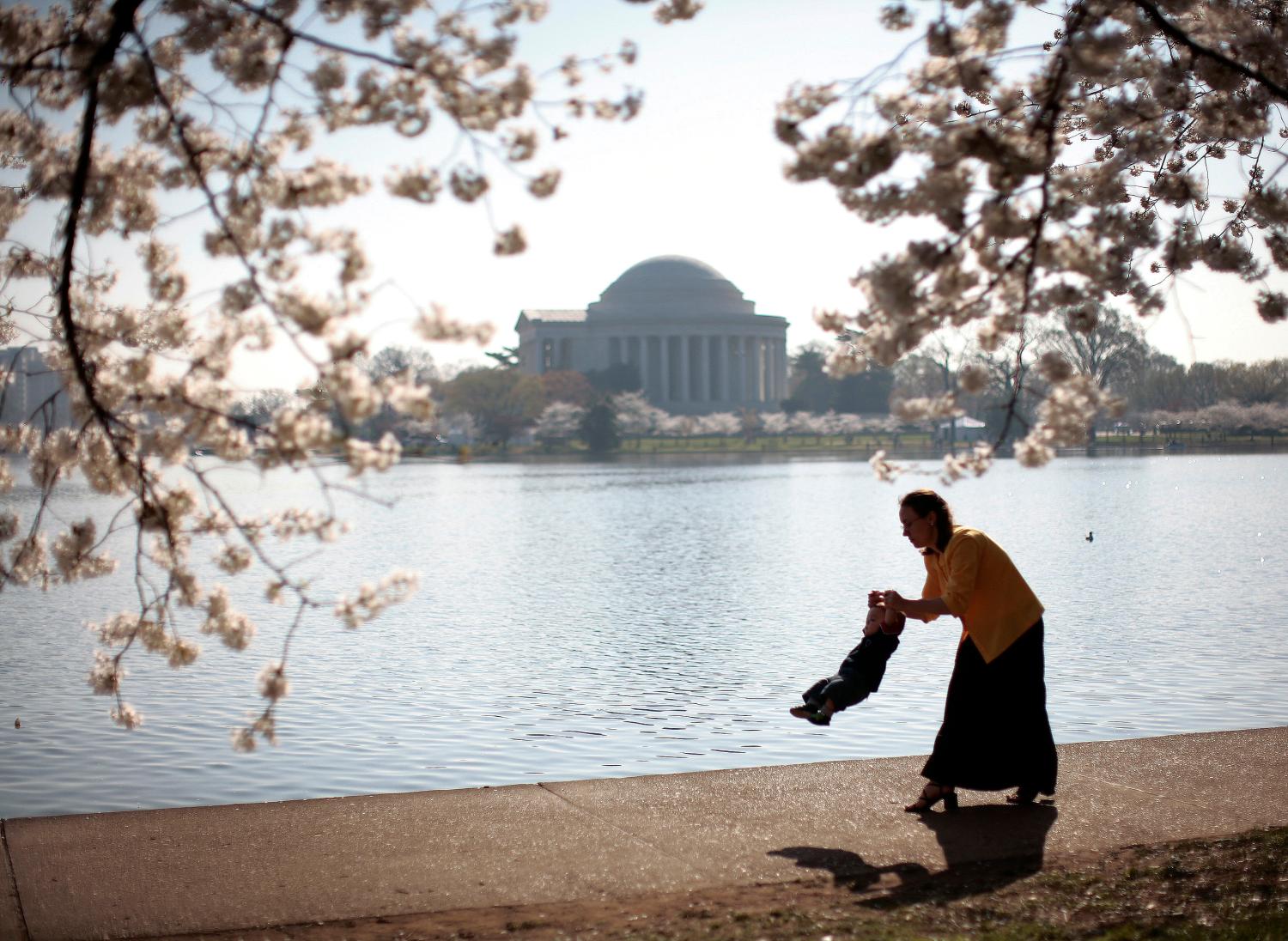 A mother swings her young son as they visit the cherry blossoms along the tidal basin in Washington April 2, 2007.  REUTERS/Jason Reed   (UNITED STATES) - GM1DUYKXVVAA