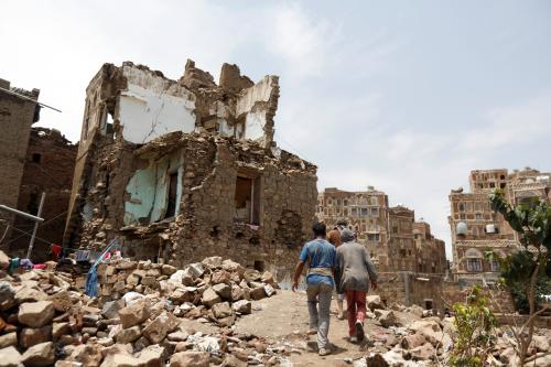 People walk past a house destroyed by an air strike in the old quarter of Sanaa, Yemen August 8, 2018. Picture taken August 8, 2018. REUTERS/Khaled Abdullah