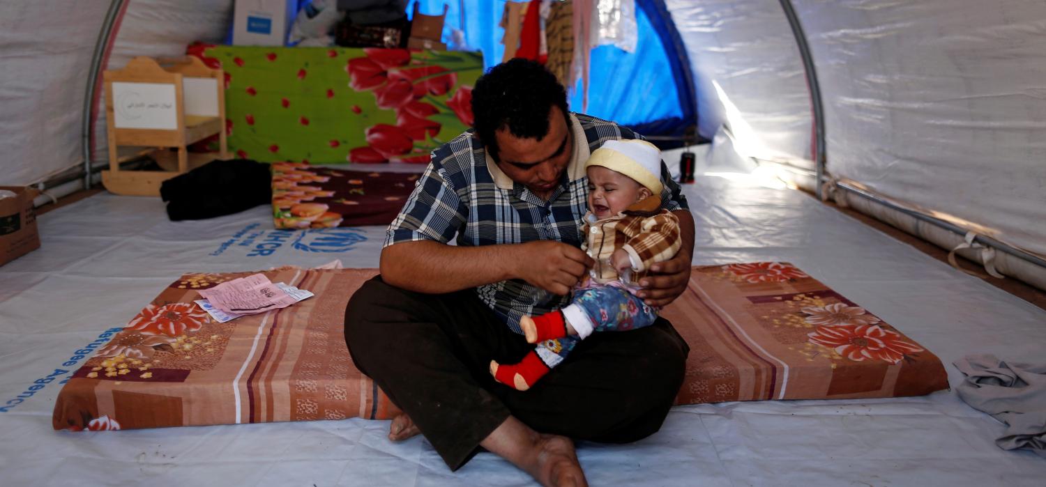 Furaq, 22, who fled from Mosul, holds his eight-moth-old son Yasser, who was born under Islamic State rule and has no identity documents recognised by Iraqi authorities, in Khazer refugee camp, Iraq November 11, 2016. REUTERS/Zohra Bensemra SEARCH "CALIPHATE CHILDREN" FOR THIS STORY. SEARCH "WIDER IMAGE" FOR ALL STORIES.  - S1BEUMYRHRAA