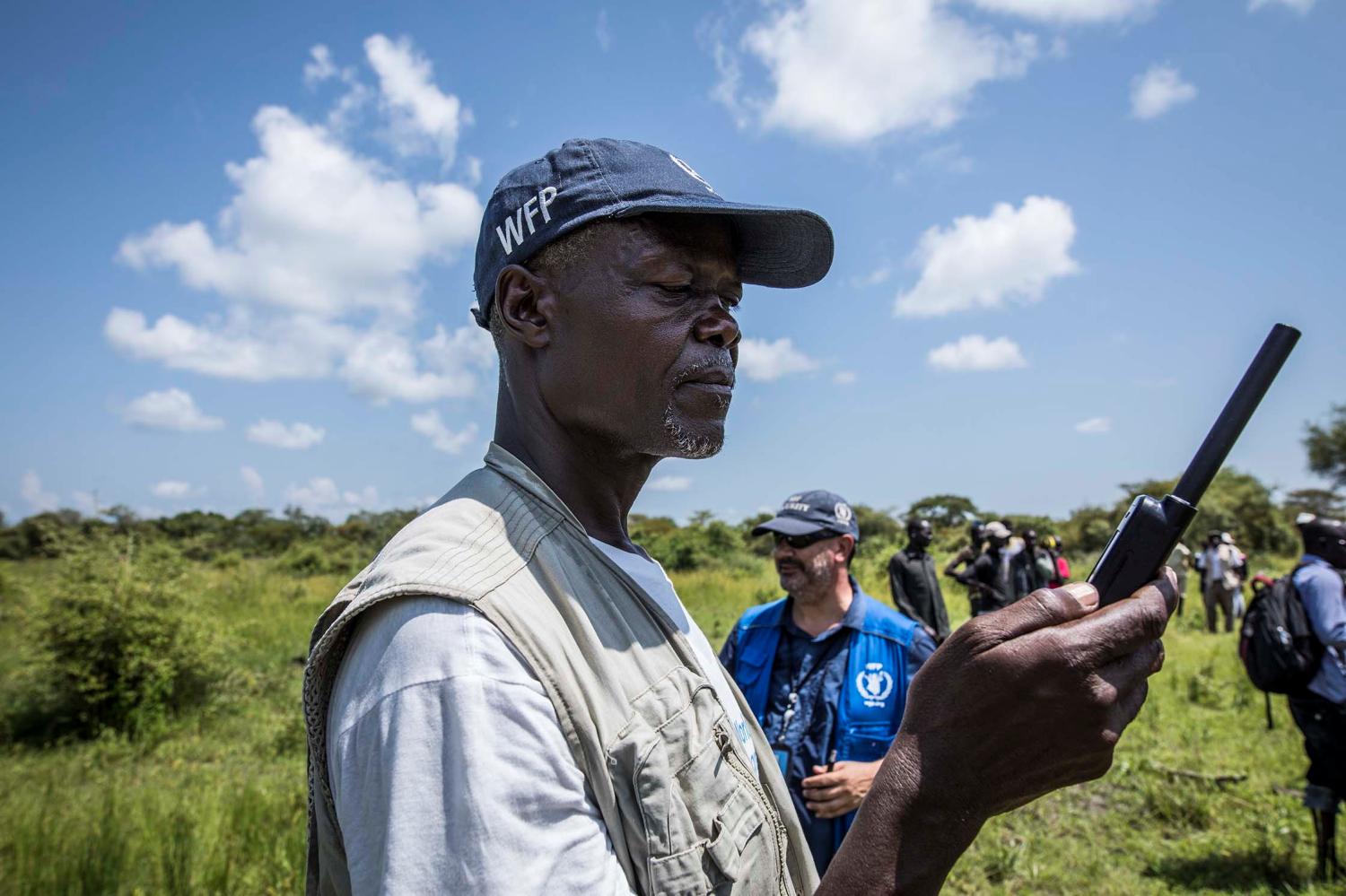 A World Food Programme employee uses a satellite phone to coordinate a U.N's World Food Programme (WFP) food aid air drop near the town of Katdalok, in Jonglei State of South Sudan July 30, 2018. REUTERS/Denis Dumo - RC172BCB7890