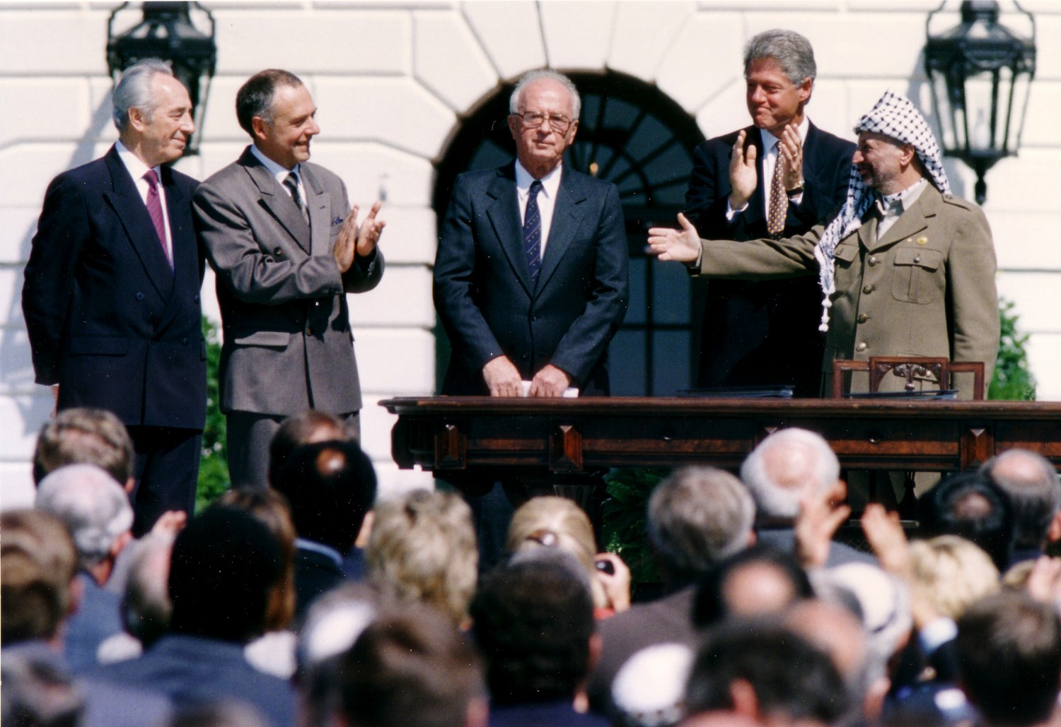 PLO Chairman Yasser Arafat (R) gestures to Israeli Prime Minister Yitzhak Rabin (3rd R), as U.S. President Bill Clinton (2nd R) stands between them, following their handshake after the signing of the Israeli-PLO peace accord, at the White House in Washington September 13, 1993. Also in picture is Israeli Foreign Minister Shimon Peres (L). REUTERS/Gary Hershorn (UNITED STATES - Tags: POLITICS) - GM1E99E00JX01