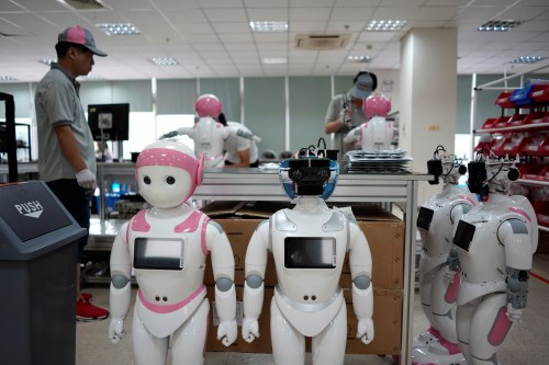 Workers put finishing touches to iPal social robots, designed by AvatarMind, at an assembly plant in Suzhou, Jiangsu province, China July 4, 2018. Designed to offer education, care and companionship to children and the elderly, the 3.5-feet tall humanoid robots come in two genders and can tell stories, take photos and deliver educational or promotional content. Picture taken July 4, 2018.REUTERS/Aly Song - RC1F91AB4DD0