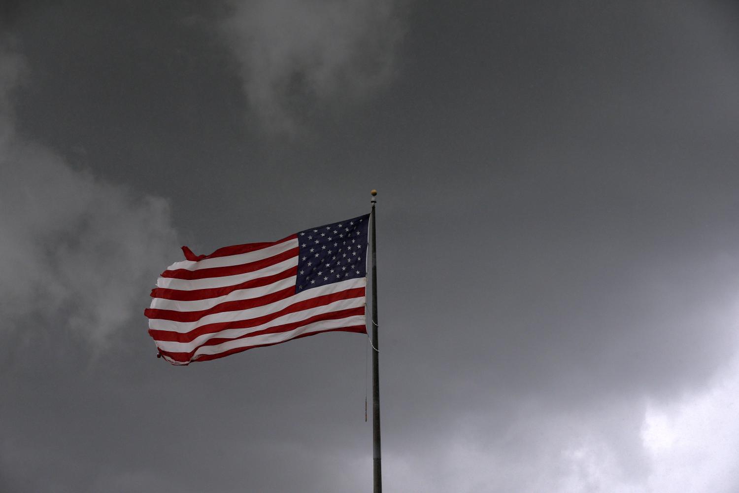 Storm clouds loom over an American flag in Convent, Louisiana, U.S., June 11, 2018. Picture taken June 11, 2018. REUTERS/Jonathan Bachman - RC17A0081E00