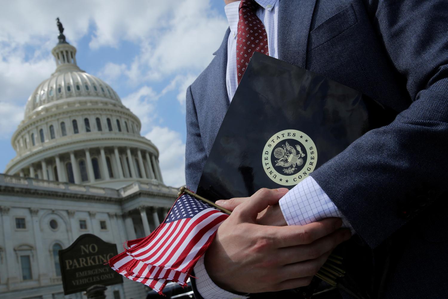 FILE PHOTO: A congressional aide holds flags to give to participants at rally at the U.S. Capitol in Washington, U.S. May 21, 2018.  REUTERS/Jonathan Ernst/File Photo - RC136D9C88F0