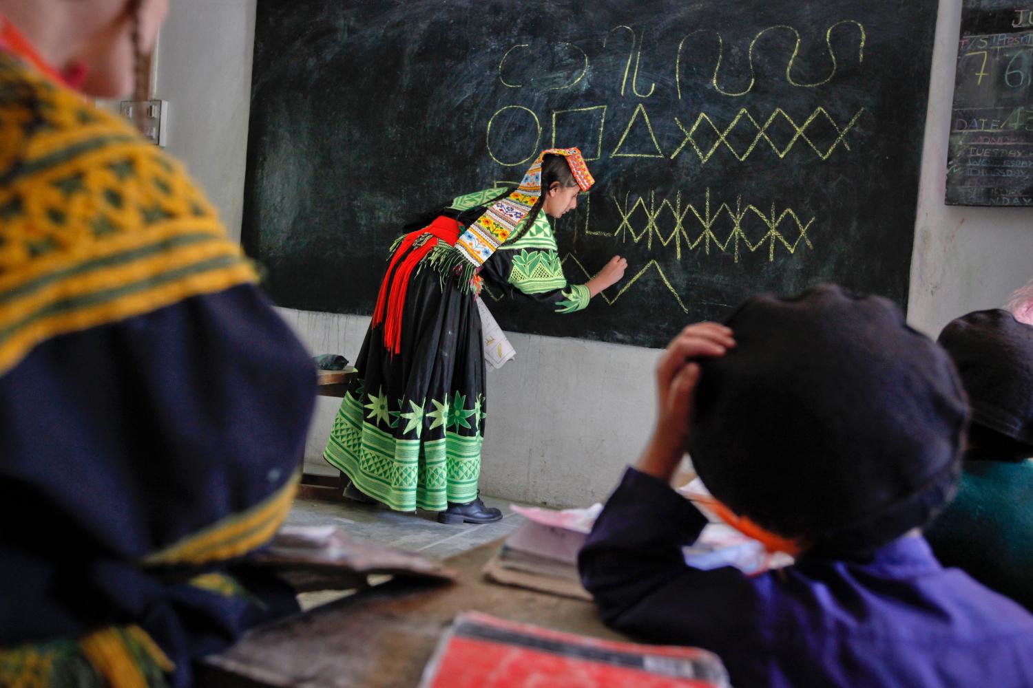 Teacher Noorzia Khan, 16, writes letters from the Kalasha alphabet on a blackboard during a lesson at the Kalasha Dur school and community centre in Brun village, located in Bumboret Kalash valley October 13, 2011. Nestled among the valleys of Pakistan's mountainous northwest, the Kalash are a tiny religious community that claim descent from Alexander the Great's army, and say they are under increasing pressure to convert to Islam. The Kalash, who number about 3,500 in Pakistan's population of 180 million, are spread over three valleys along the border with Afghanistan and are known for their distinctive dress, vibrant religious festivals, and polytheism. To match Feature PAKISTAN-KALASH/  REUTERS/Rebecca Conway   (PAKISTAN - Tags: SOCIETY EDUCATION TPX IMAGES OF THE DAY) FOR BEST QUALITY IMAGE: ALSO SEE GM1E9720MFD01 - GM1E7AK1E7B01