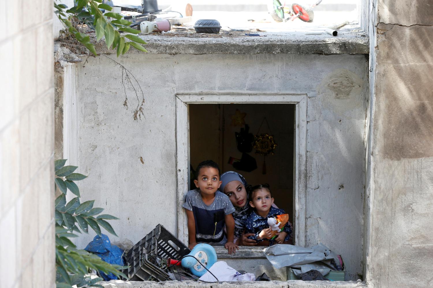 27-year-old Syrian refugee Alaa Masalmeh and her children, 5-year-old Samer and 3-year-old Mieral, look out of their home's window in Amman, Jordan, August 1, 2018. Picture taken August 1, 2018. REUTERS/Muhammad Hamed - RC18B300D870
